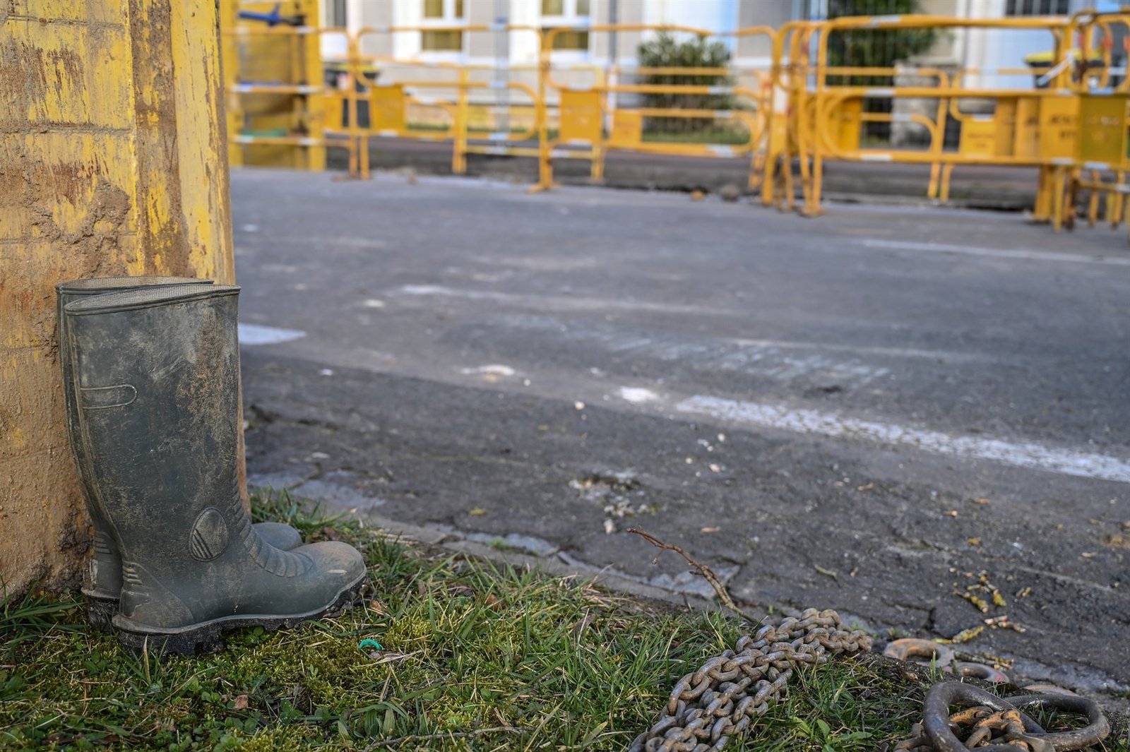 Bottes de chantier et chaîne posées au sol en fin de journée