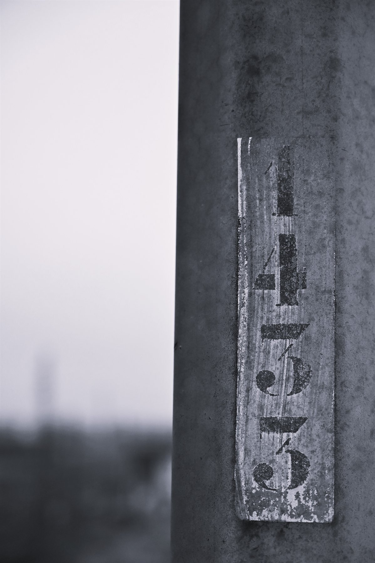Repère peint à la main sur un poteau de béton, noir et blanc