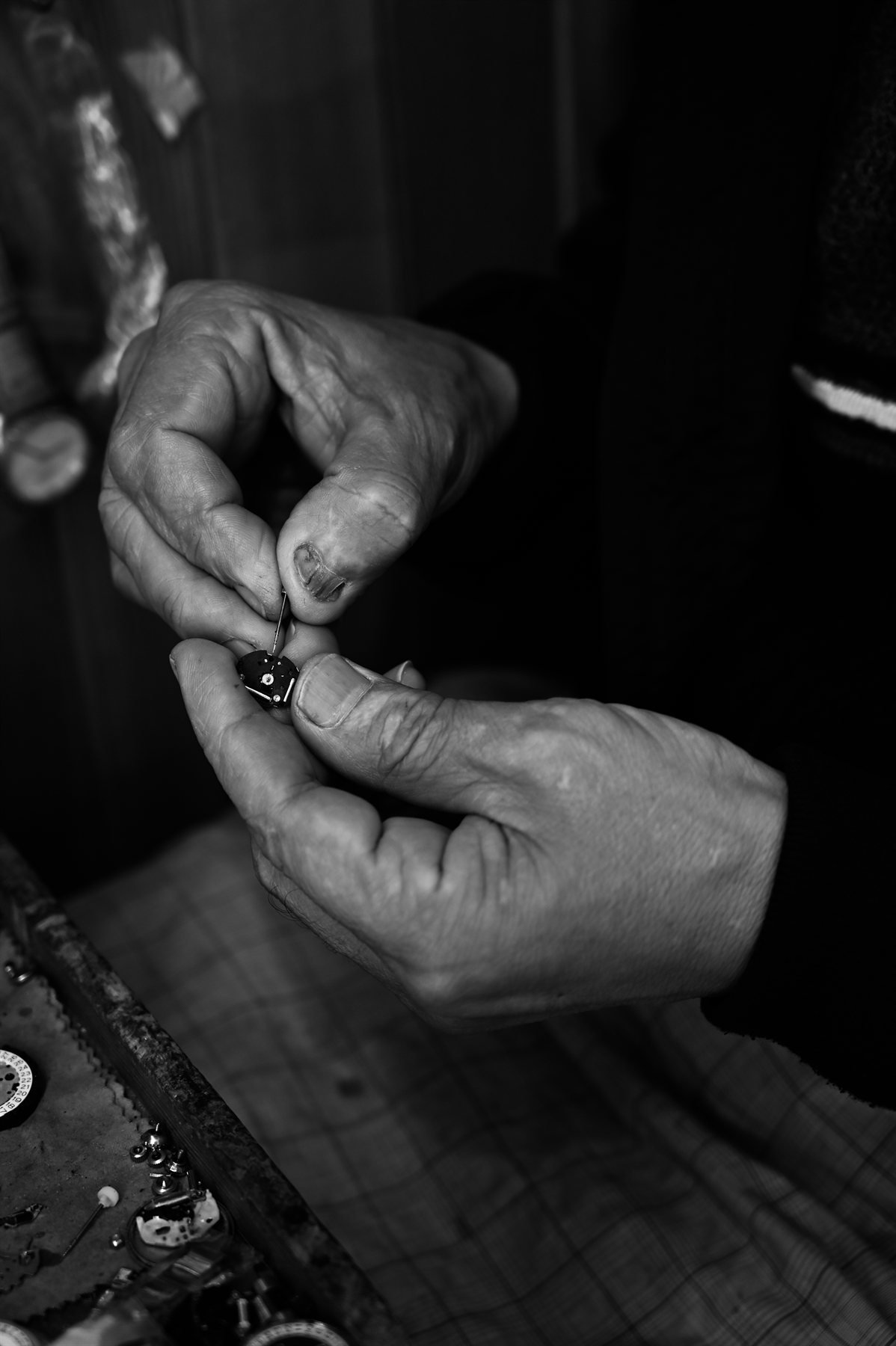 Mains d'un horloger ajustant un mécanisme de montre, noir et blanc