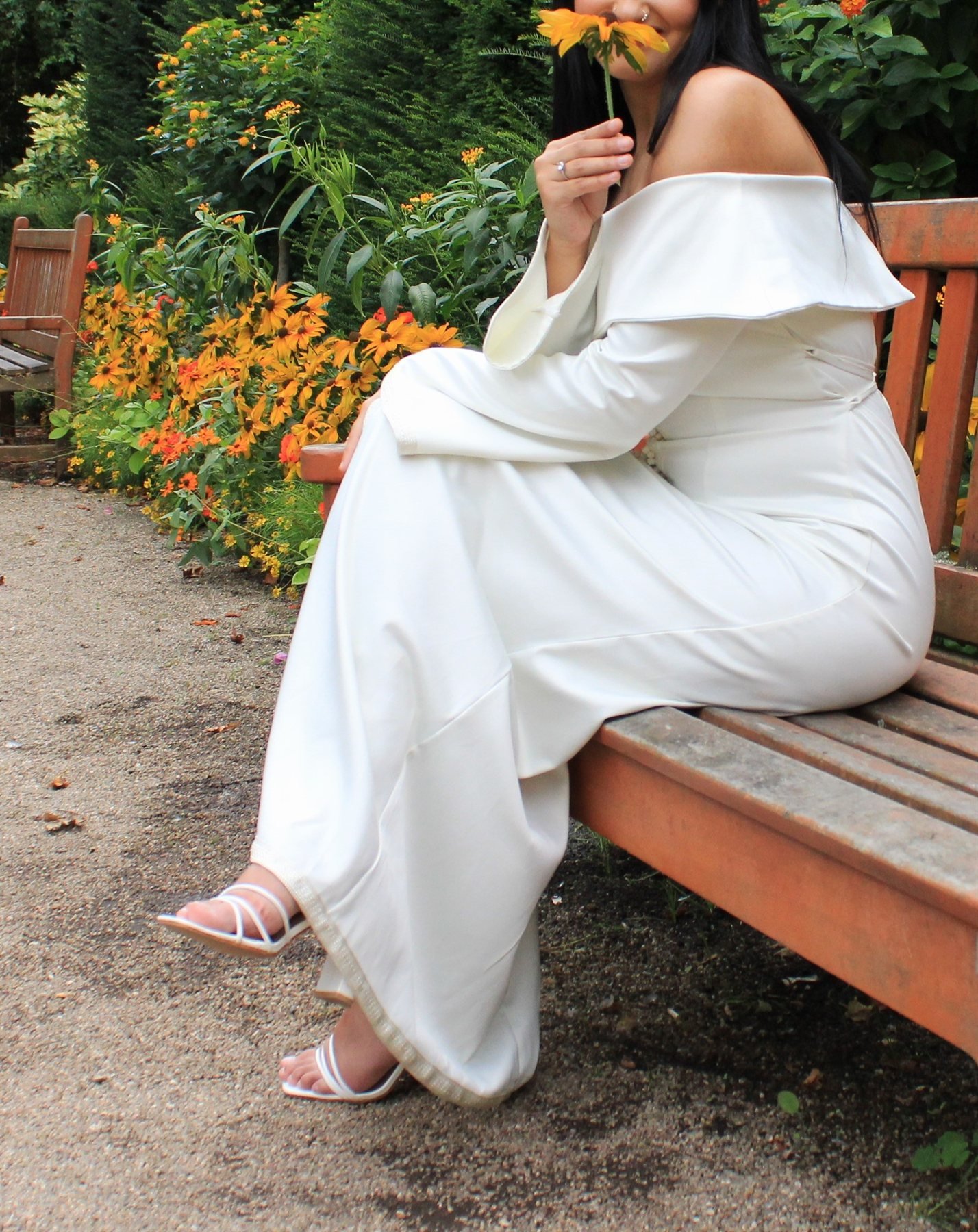 Assise sur un banc, une fleur à la main